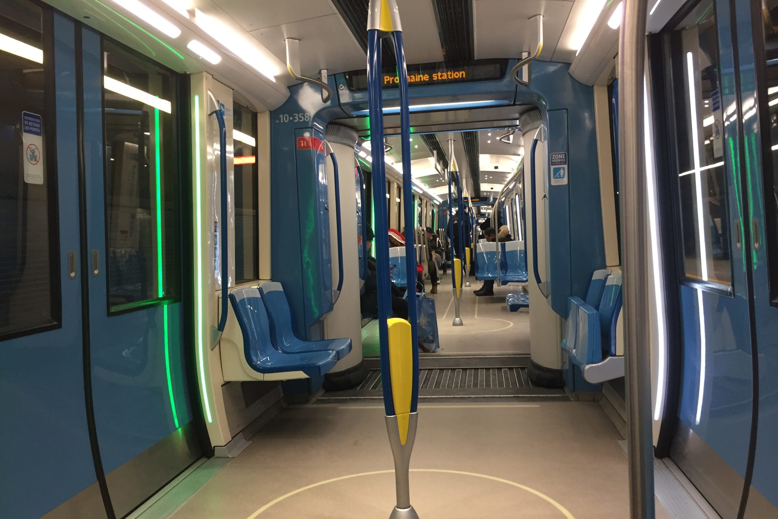 Lights beside the doors on the left are lit in green to indicate they will open at the next station. The doors on the right side of the train are lit in white.